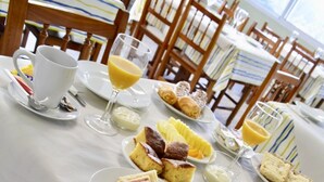 Ein Esstisch, reichhaltig gedeckt mit Speisen, darunter Sandwiches, Gebäck und ein Glas Orangensaft.