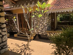 A stone building with a tiled roof, a small tree, and a bench. - Plumeria Luxury Villas Udawalawe (Udawalawa)