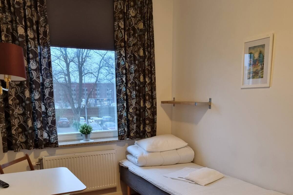 Una habitación pequeña y acogedora con una cama individual, una mesa y una silla.