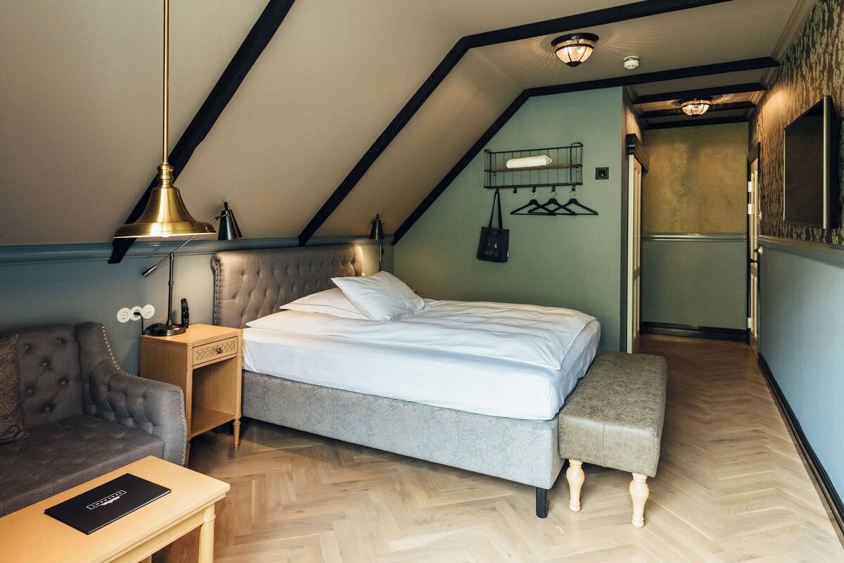 Une chambre à coucher avec un lit, une table de chevet, une lampe et un banc.