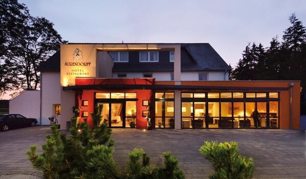 A hotel with a modern facade, large glass windows, and a well-lit entrance. - AKZENT Hotel Haus Surendorff (Bramsche)