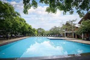 A swimming pool with lounge chairs and a building in the background.