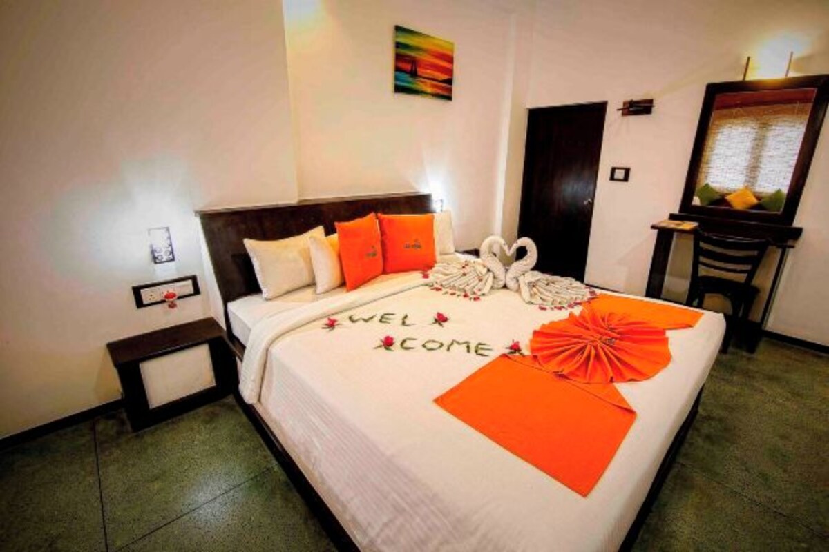 A neatly made bed with a welcome mat, pillows, and decorative swans.