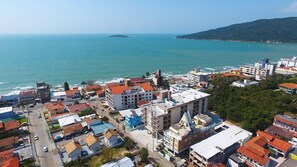 A coastal town with buildings close to the sea, featuring a mix of residential and commercial structures. - Ingleses Apart Hotel (Florianópolis)