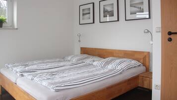 Cozy retreat with a neatly made bed and minimalist decor, featuring a wooden bed frame and a small window.