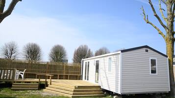 Une maison mobile de plain-pied, dotée d’un petit porche et d’une rampe menant à l’entrée.