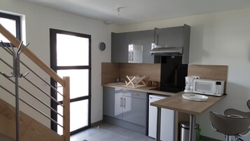 Una cocina moderna con armarios grises, una estufa negra y un microondas blanco.