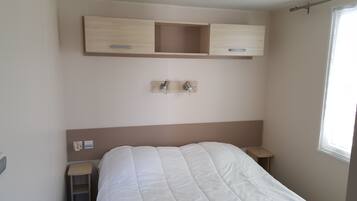 A bedroom with a bed, bedside tables, a headboard, and built-in wooden cabinets above the bed.