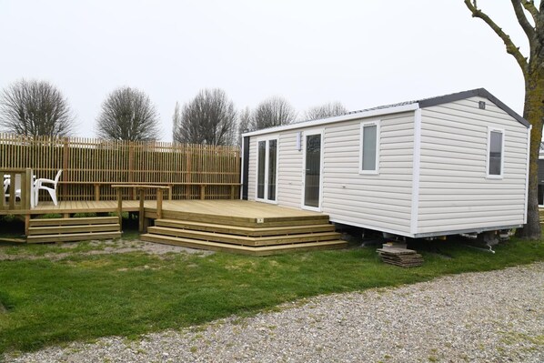 A mobile home with a wooden deck and a small porch. - Camping Le Pré Fleuri (Le Crotoy)