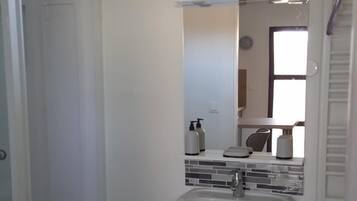 A bathroom with a pedestal sink, a mirror, and a shower enclosure.