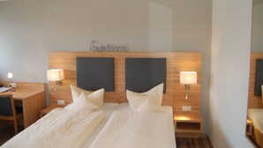 A hotel room with two beds, a desk, and a chair.