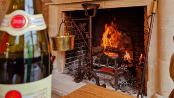 Una bottiglia di vino su un tavolo di legno, con un camino sullo sfondo.