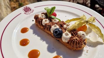 Ein Dessert auf einem Teller mit einem Logo, umgeben von einem Tisch und Stühlen.