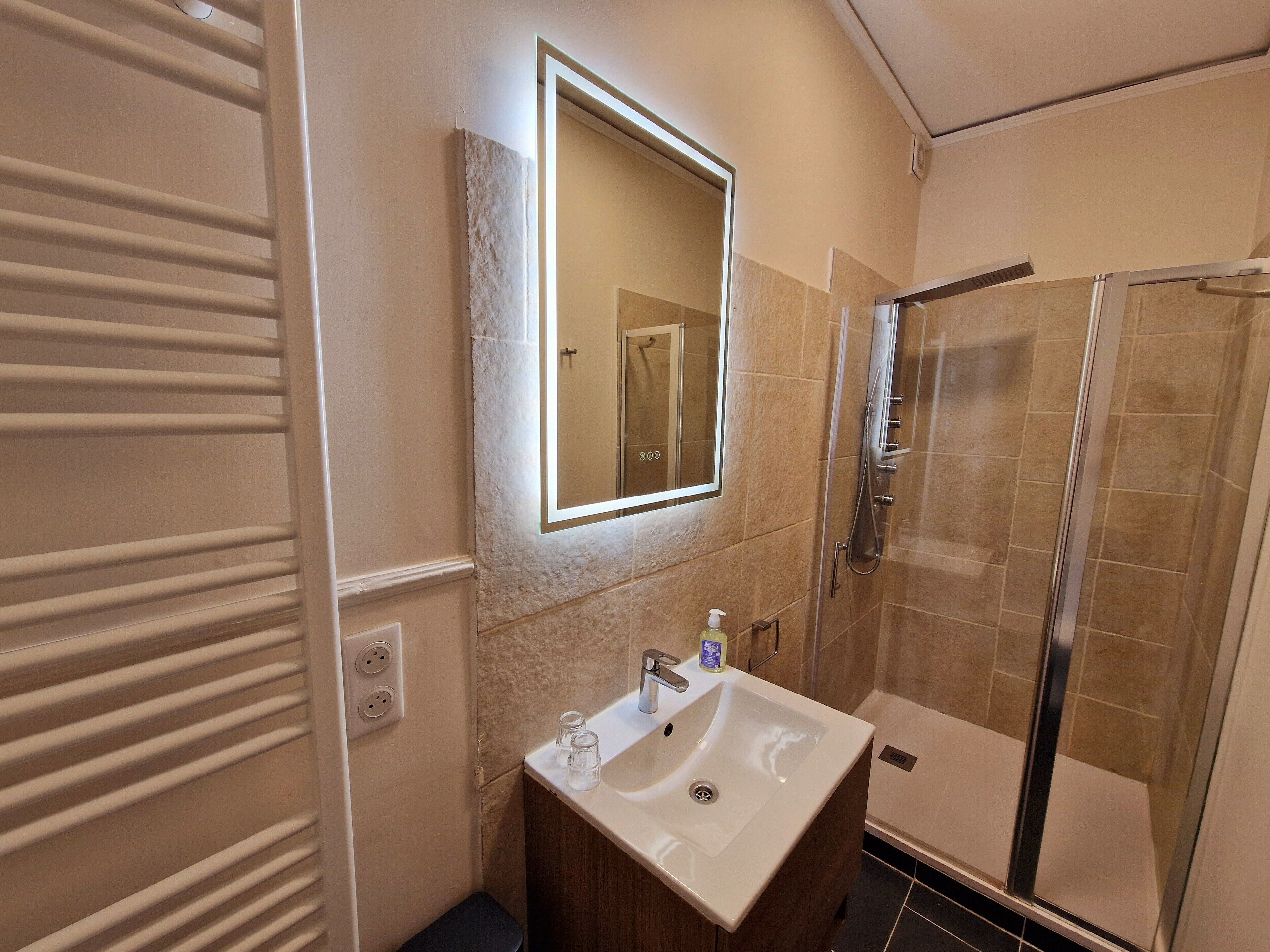 A bathroom with a white sink, a mirror, and a glass shower enclosure.