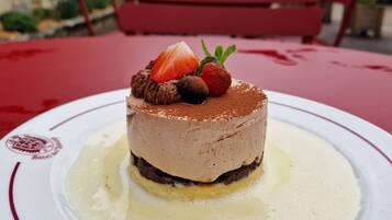 A dessert on a plate with a red tablecloth, set outdoors with a red bench and stone buildings in the background.