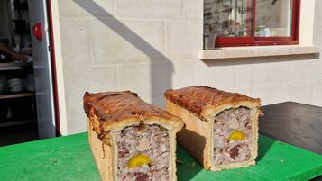 Two meat pies on a green cutting board in front of a building with a window.
