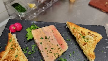 Una tabla de pizarra con una rebanada de pan, rábanos y un plato de carne.