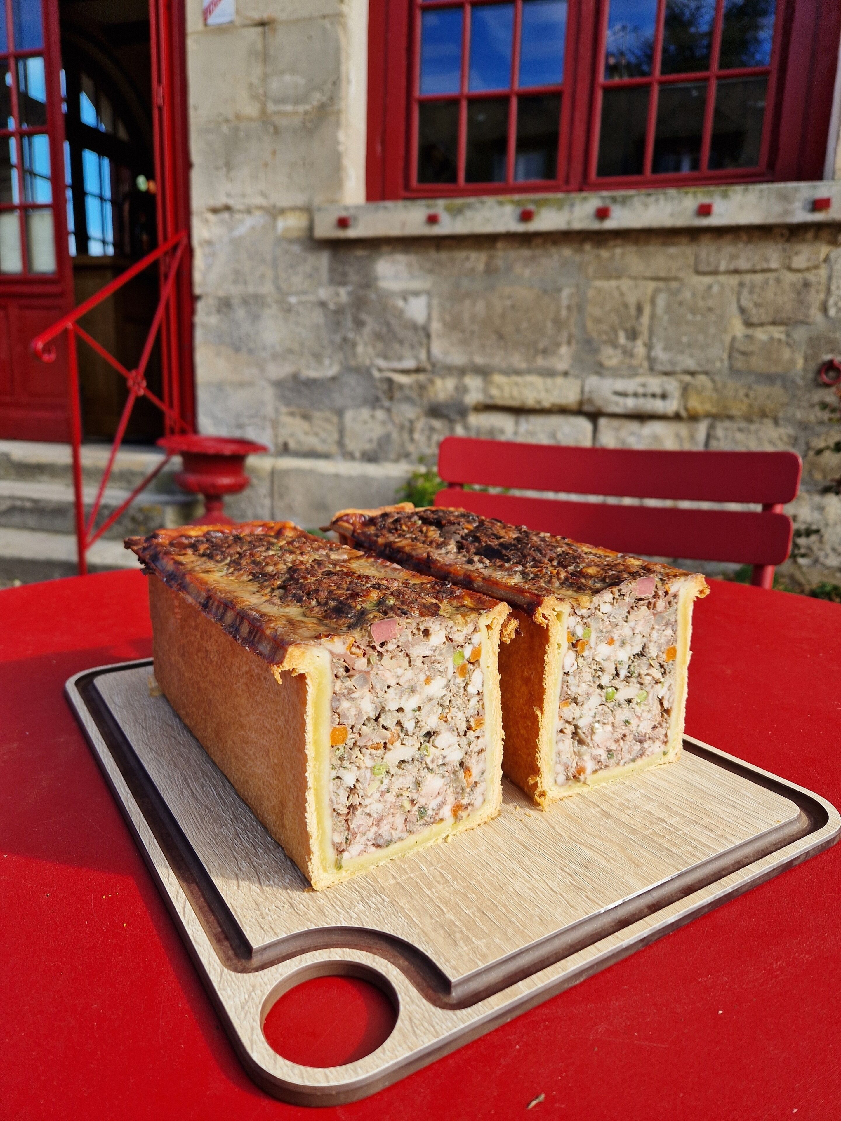 Un pastel de carne sobre una tabla de cortar de madera sobre una mesa roja.