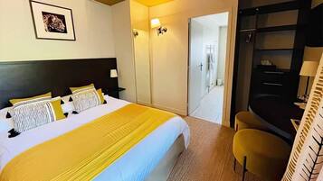 Une chambre d’hôtel comprenant un lit, des tables de chevet, un miroir, une armoire et une salle de bain visible à travers une porte ouverte.