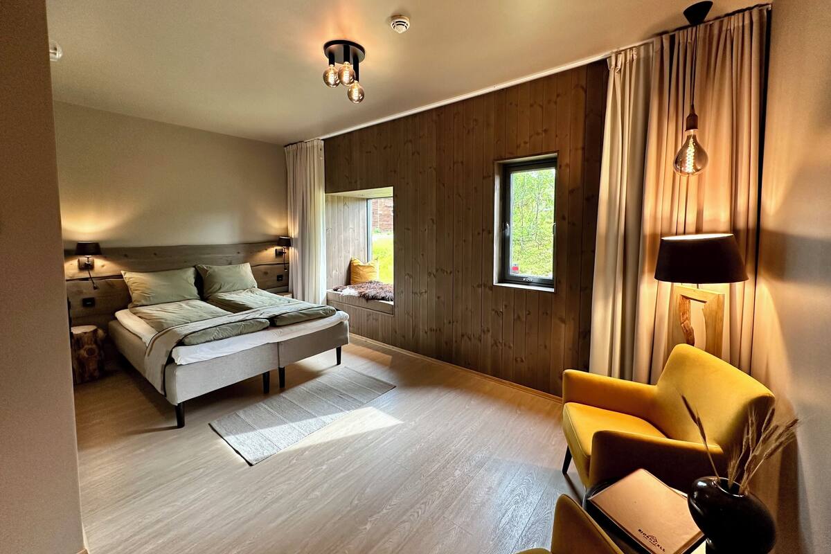 A modern bedroom with a bed, bedside tables, a window, a chair, and a lamp.