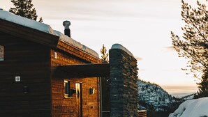 A wooden cabin with a stone wall and a wooden door. - Bjørnfjell Mountain Lodge (Alta)