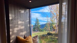 A room with a window seat, wooden paneling, and a view of a forested area. - Bjørnfjell Mountain Lodge (Alta)