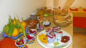 A table with various food items including fruits, yogurt, and bread. - Cloris Guest House (Noto)