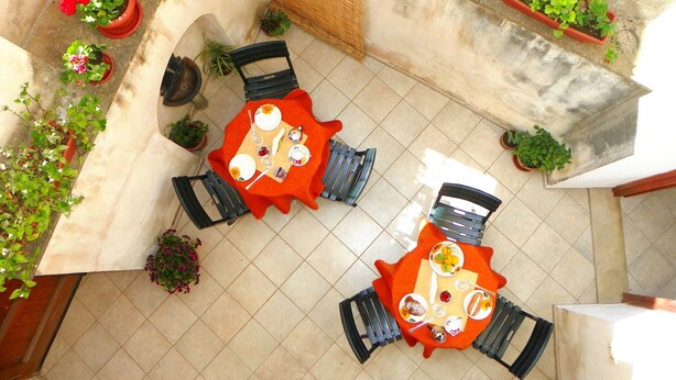 An outdoor dining area with two tables, chairs, and potted plants. - Cloris Guest House (Noto)