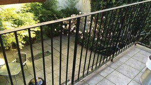Un balcon avec une balustrade en métal, un barbecue et un pot de fleurs.