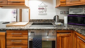 Une cuisine moderne avec des meubles en bois, des plans de travail en granit, des appareils électroménagers en acier inoxydable et un panneau indiquant les règles à respecter dans la cuisine.