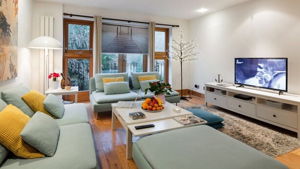 Un salon moderne avec un canapé, une table basse et un téléviseur.