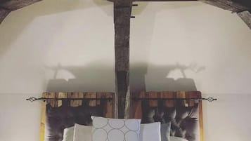 Un dormitorio con techo de madera, una cama con ropa blanca y un cabecero con diseño estampado.