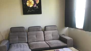 A modern living room with a grey sectional sofa, a wooden coffee table, and two grey ottomans.
