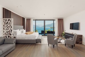 A modern hotel room with a large bed, a sofa, a TV, and a balcony with a view of the sea. - Monte Palm Beach (Durasevici)
