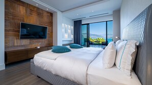 A modern bedroom with a large bed, a TV mounted on a wooden panel wall, and a balcony with a view. - Monte Palm Beach (Durasevici)