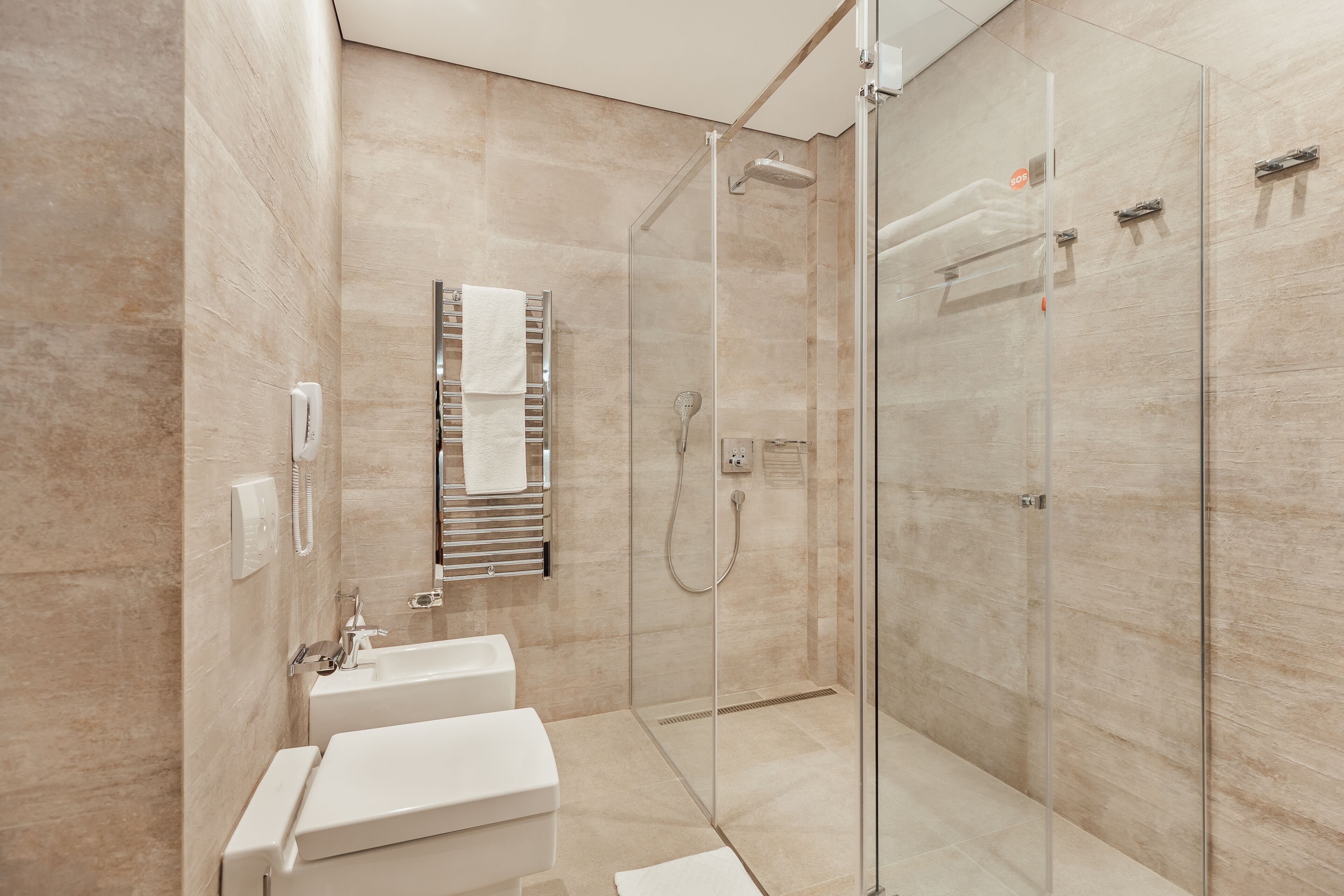 A modern bathroom with a glass-enclosed shower, a sink, and a towel rack.