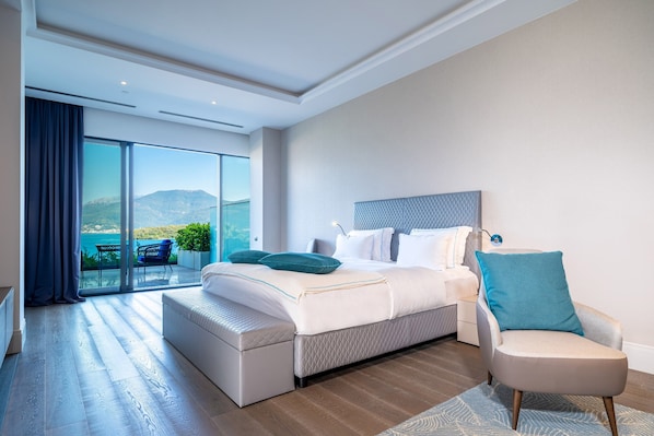 Un dormitorio moderno con una cama grande, una zona de estar y un balcón con vistas.