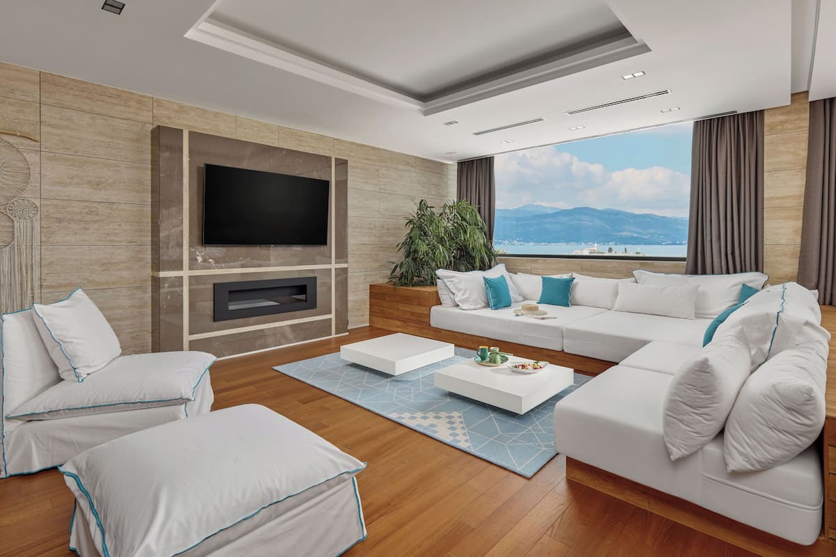 A modern living room with a large TV, a sofa set, and a view of the mountains.