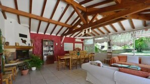 Amplia sala de estar con techos altos, chimenea, comedor y un gran ventanal con vistas al exterior.
