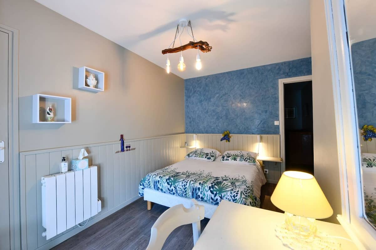 Ein Schlafzimmer mit einem Bett, Nachttischen, einer Lampe, einem Heizkörper und Wandregalen.