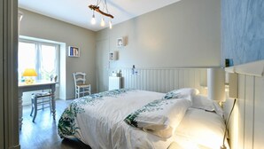 Un dormitorio con cama, mesita de noche, lámpara y ventana con vistas.