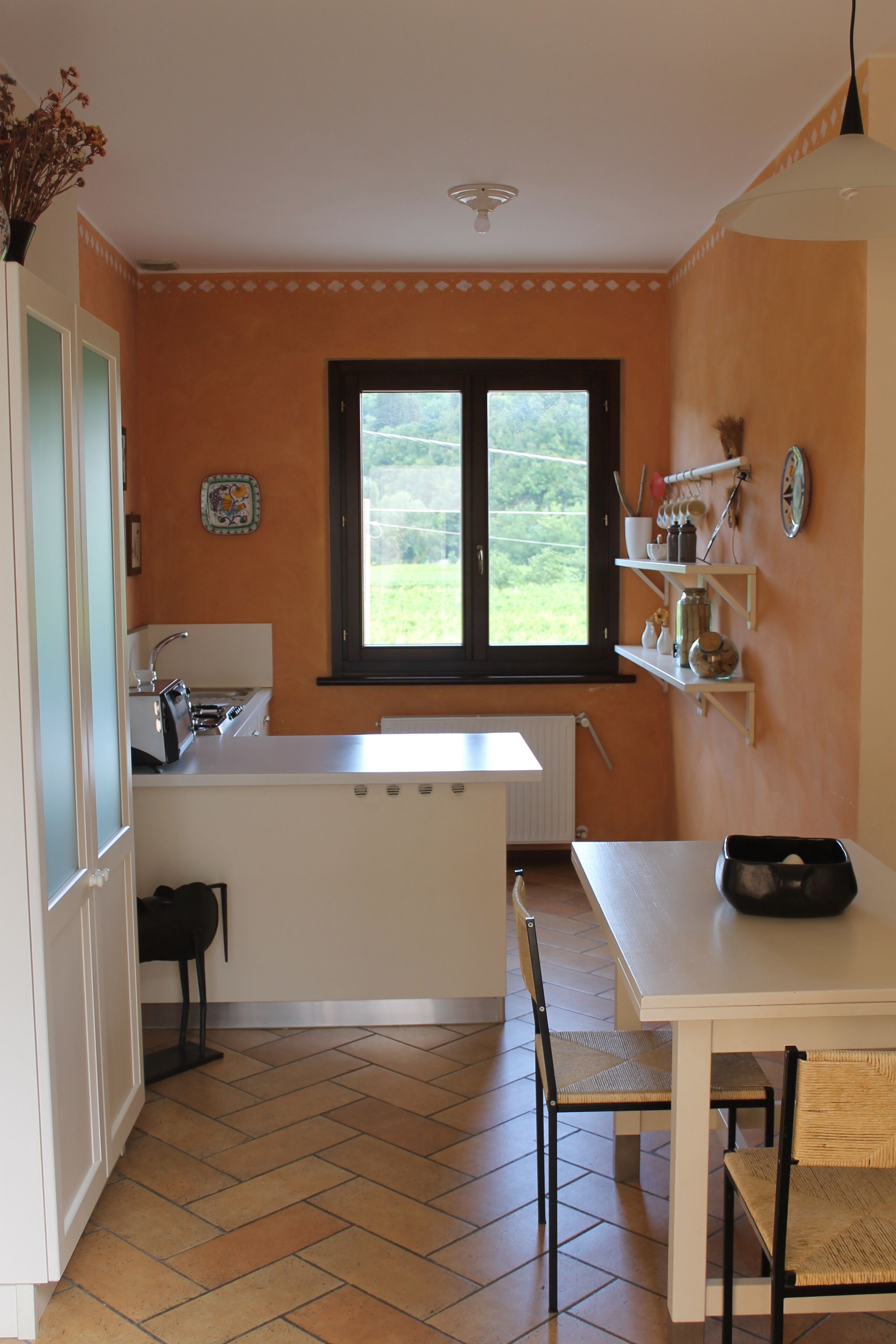 A compact kitchen with a window, a white countertop, and a dining area with a table and chairs.