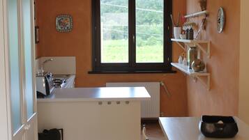 A compact kitchen with a window, a white countertop, and a dining area with a table and chairs.