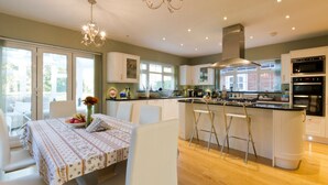 Une cuisine moderne avec des meubles blancs, un îlot central doté de tabourets de bar et un coin repas avec une table dressée pour deux personnes.