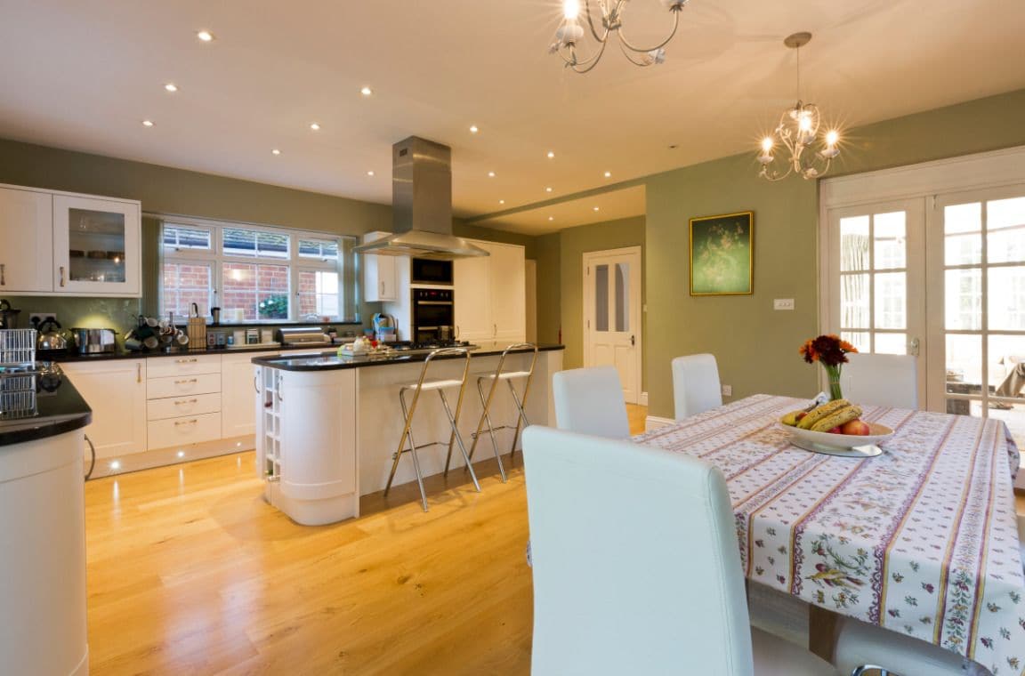 A modern kitchen with white cabinets, a central island, and a dining area with a table set for two.