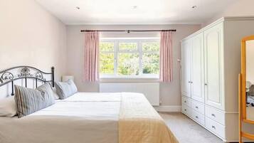 Un dormitorio con cama doble, armario y ventana con cortinas.