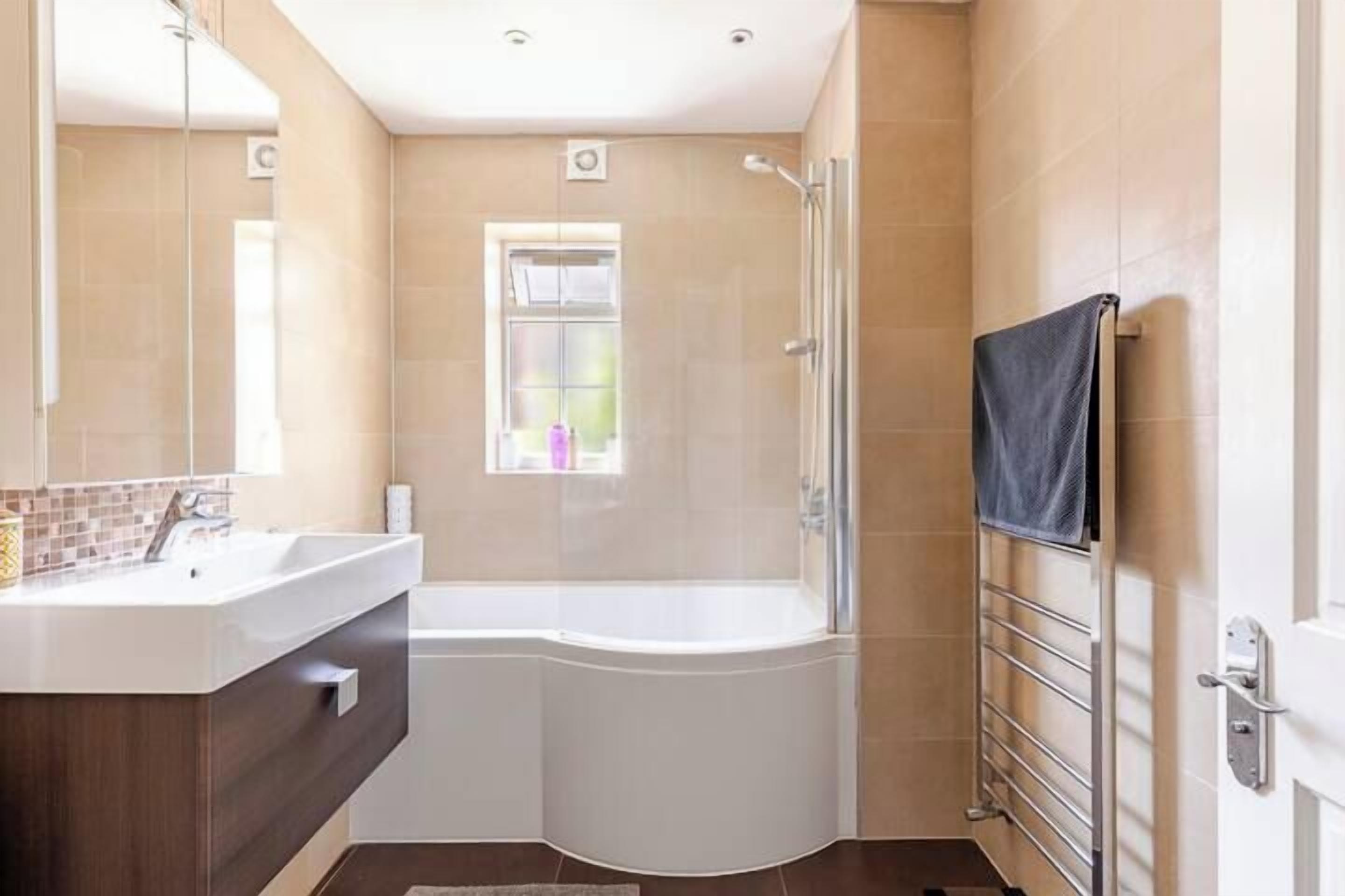 Une salle de bain moderne équipée d’une douche, d’un lavabo et d’un porte-serviettes.