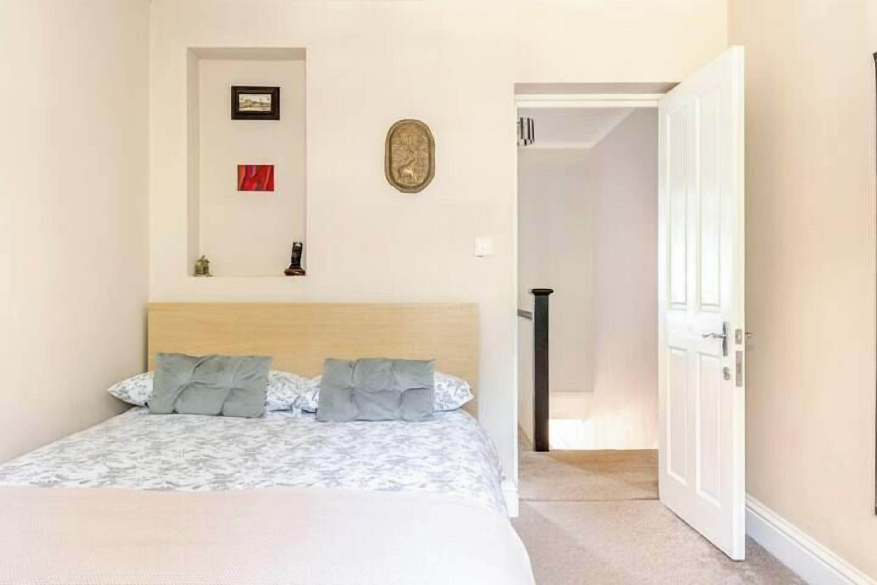 Un dormitorio con cama, puerta, pasillo y un pequeño adorno en la pared.