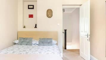 Un dormitorio con cama, puerta, pasillo y un pequeño adorno en la pared.