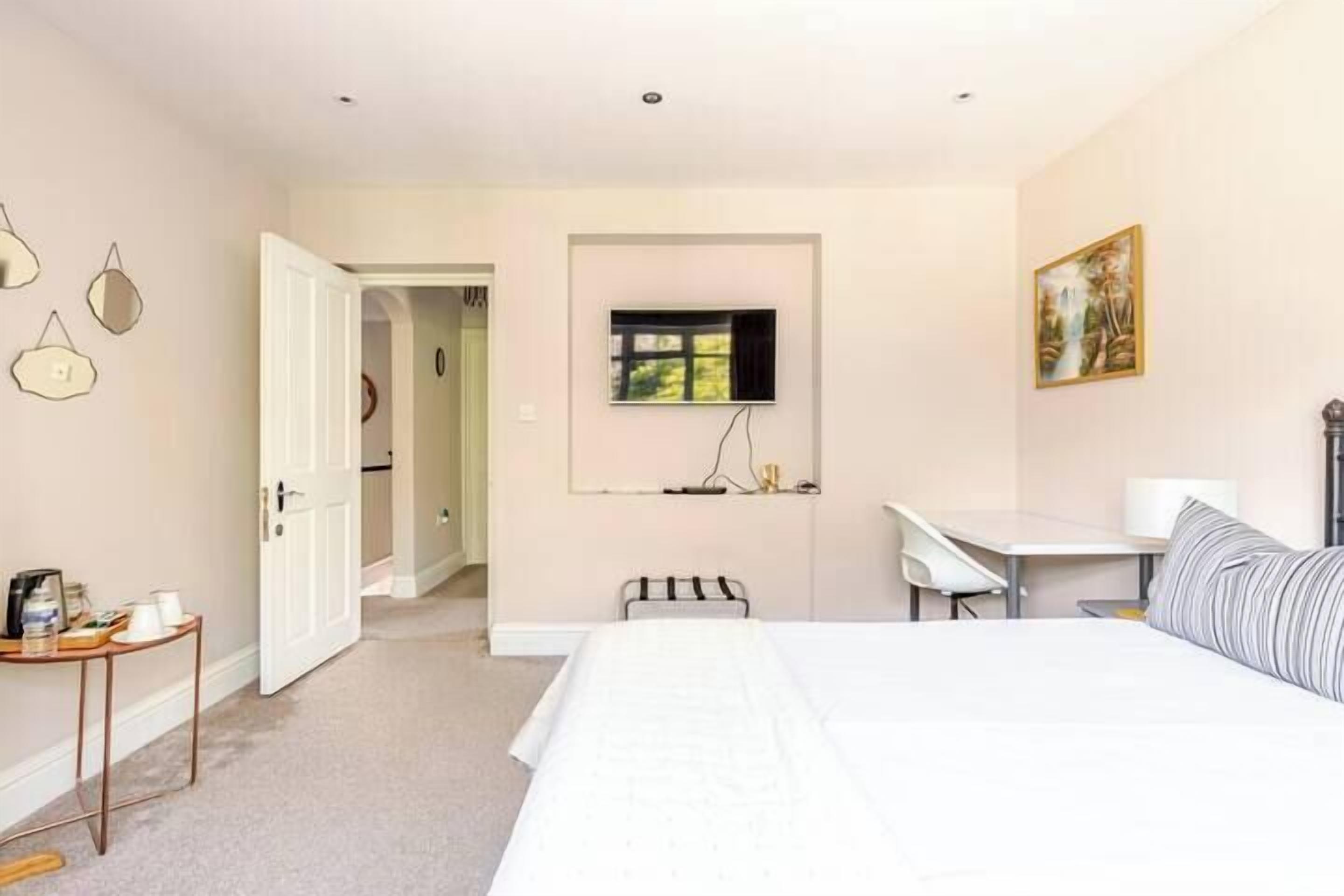 A bedroom with a bed, a desk, a chair, and a television.